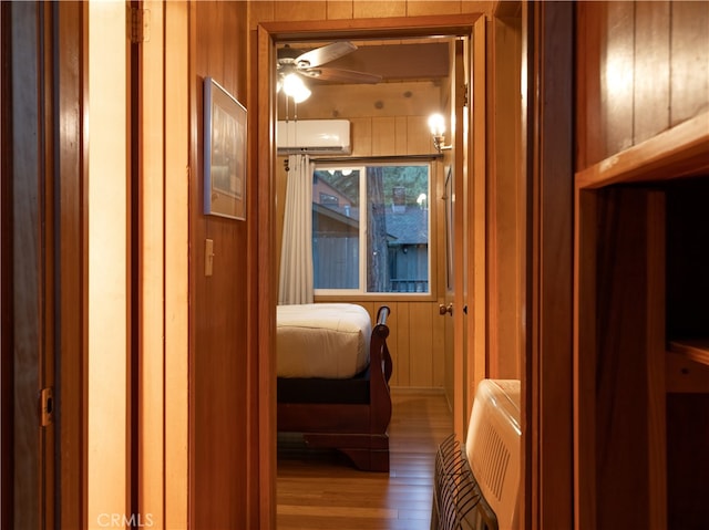 corridor featuring wooden walls, light hardwood / wood-style floors, and a wall unit AC