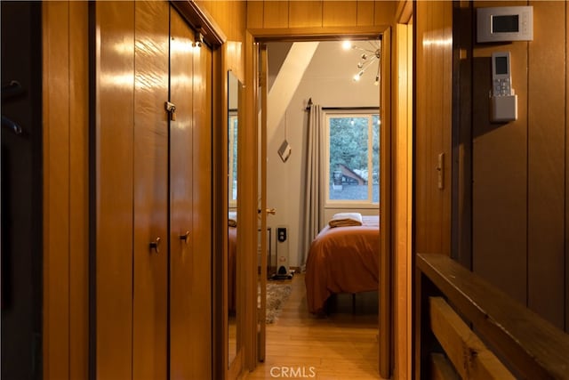 hall with light wood-type flooring and wood walls