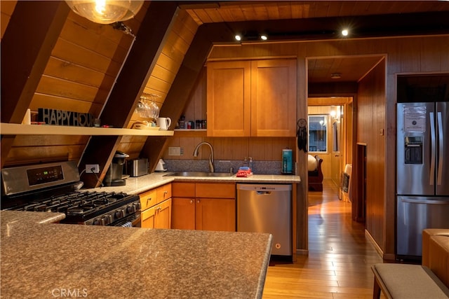 kitchen with sink, wood walls, light hardwood / wood-style flooring, stainless steel appliances, and wooden ceiling