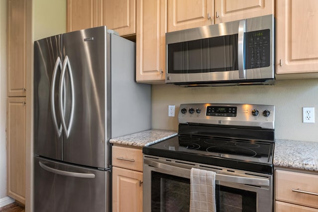 kitchen with light brown cabinetry, appliances with stainless steel finishes, and light stone counters