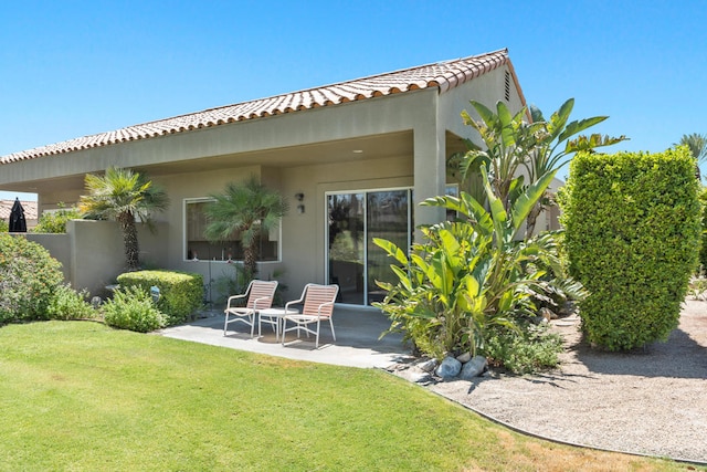 back of house with a lawn and a patio