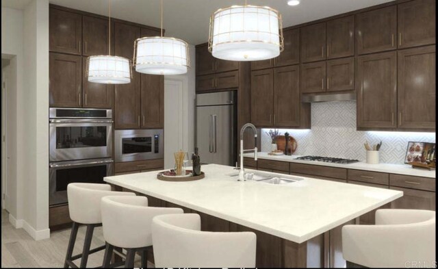 kitchen with pendant lighting, sink, tasteful backsplash, appliances with stainless steel finishes, and a kitchen bar