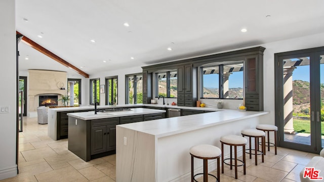 kitchen with kitchen peninsula, a premium fireplace, a kitchen island, a kitchen breakfast bar, and vaulted ceiling with beams