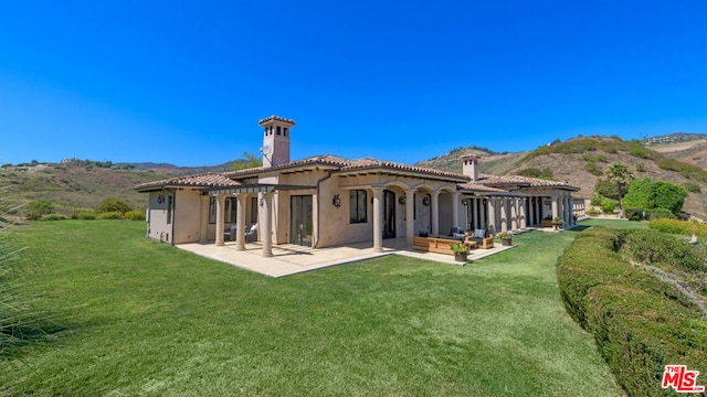 rear view of property featuring a yard, a pergola, and a patio area