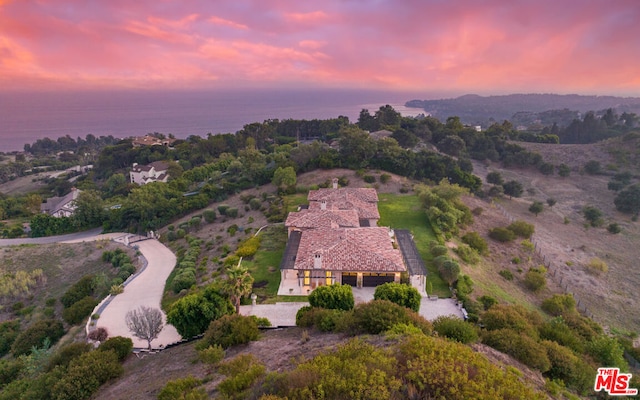 aerial view at dusk featuring a water view