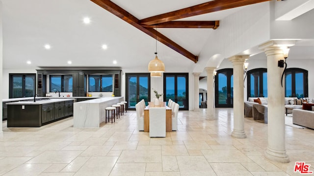 kitchen featuring pendant lighting, beamed ceiling, sink, a center island, and a breakfast bar area