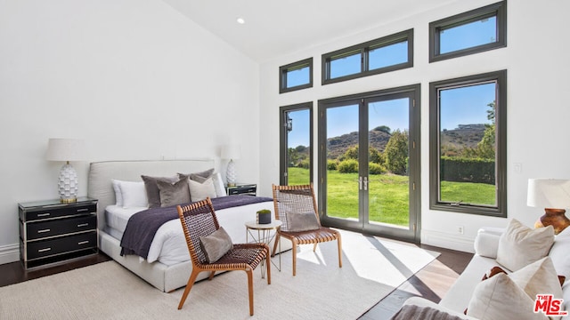 bedroom with wood-type flooring, access to outside, and high vaulted ceiling