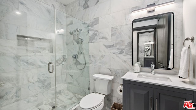 bathroom featuring tile walls, a shower with door, vanity, and toilet