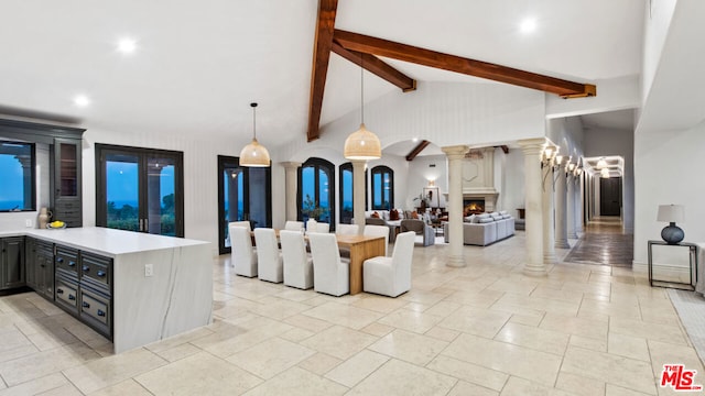 kitchen featuring pendant lighting, beam ceiling, kitchen peninsula, high vaulted ceiling, and ornate columns