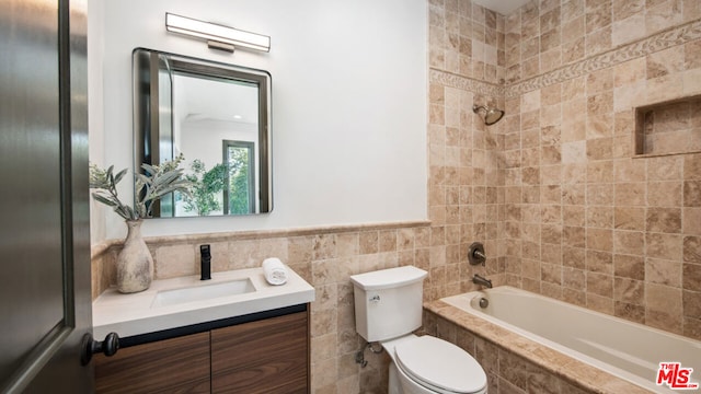 full bathroom featuring tiled shower / bath, vanity, and toilet