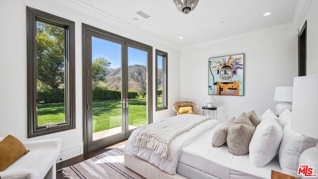 bedroom featuring ornamental molding, hardwood / wood-style floors, a mountain view, and access to exterior