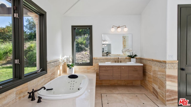 bathroom featuring tiled tub, vanity, and tile patterned flooring