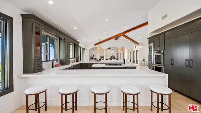 kitchen with a kitchen breakfast bar, vaulted ceiling with beams, kitchen peninsula, and a healthy amount of sunlight