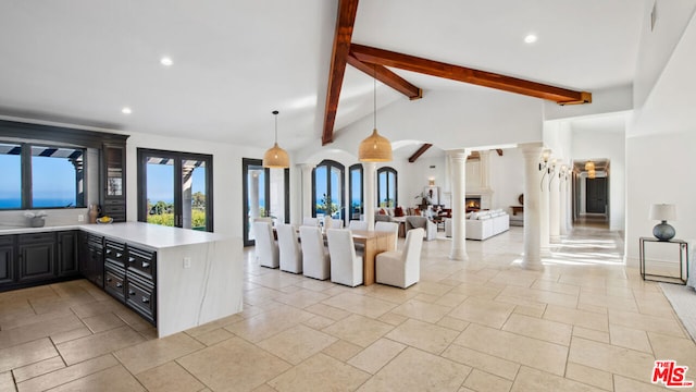 kitchen featuring ornate columns, vaulted ceiling with beams, decorative light fixtures, and kitchen peninsula