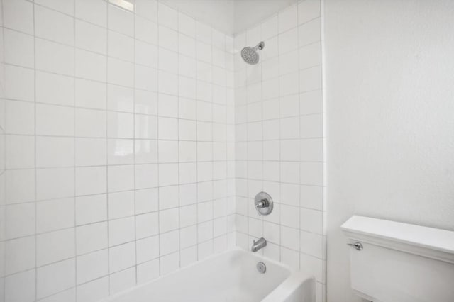 bathroom featuring tiled shower / bath and toilet