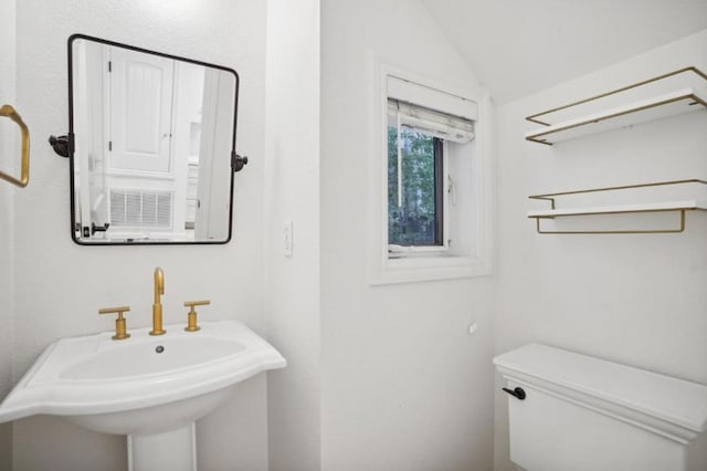 bathroom with vaulted ceiling, toilet, and sink