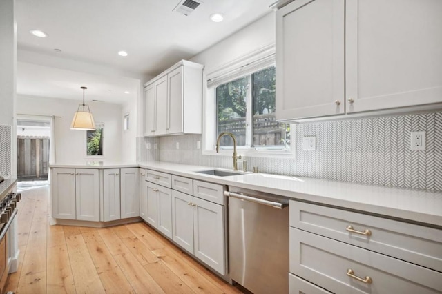 kitchen featuring white cabinetry, decorative backsplash, hanging light fixtures, stainless steel dishwasher, and light wood-type flooring