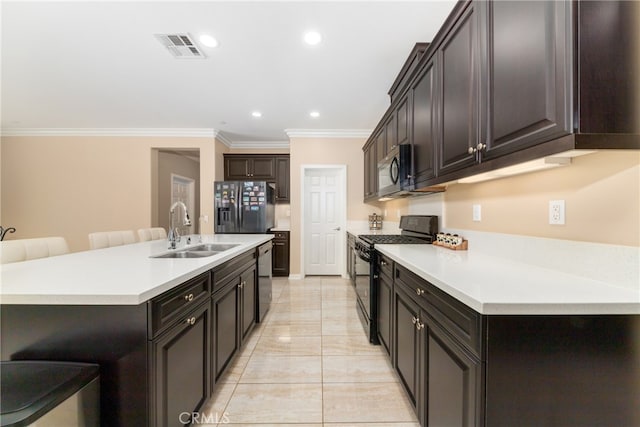 kitchen featuring sink, a kitchen breakfast bar, stainless steel appliances, a center island with sink, and crown molding