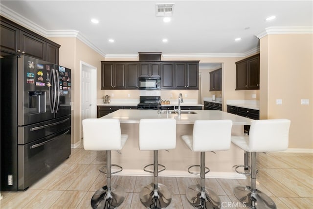 kitchen with dark brown cabinetry, a breakfast bar, sink, and black appliances