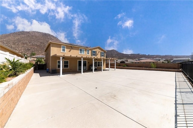21047 Iron Rail Dr, Riverside, CA 92507 - back of property featuring a fenced backyard, a mountain view, roof mounted solar panels, and a patio area