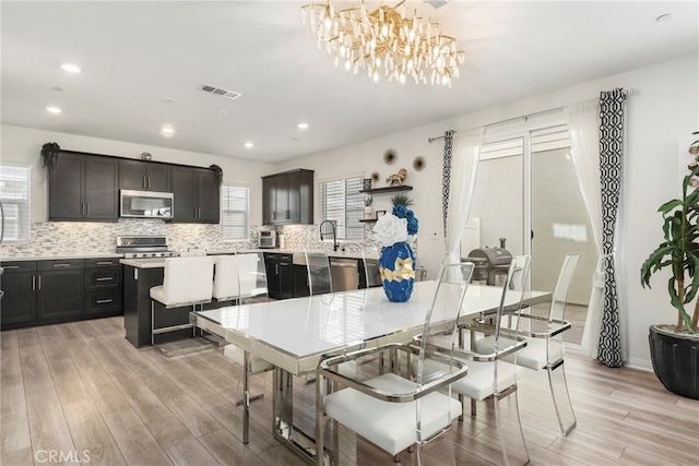 kitchen featuring a kitchen island, appliances with stainless steel finishes, decorative light fixtures, and light hardwood / wood-style floors