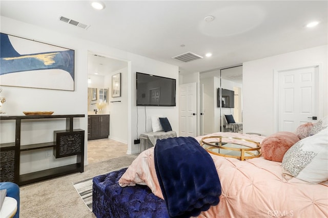 bedroom with light carpet, a closet, and ensuite bath