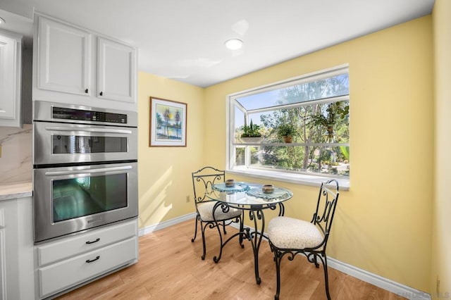 kitchen with tasteful backsplash, light hardwood / wood-style floors, white cabinetry, and double oven