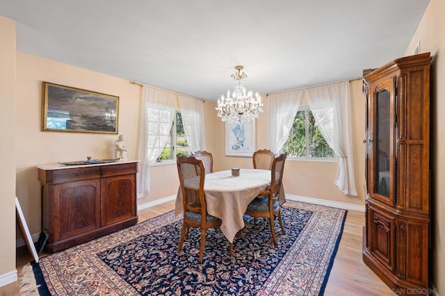 dining room featuring a healthy amount of sunlight, light wood-type flooring, and an inviting chandelier