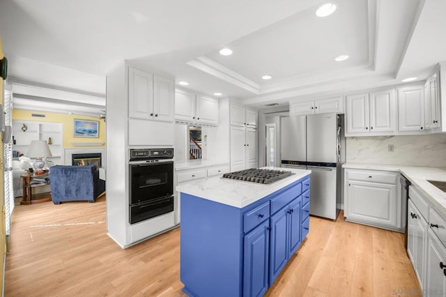 kitchen with white cabinets, a kitchen island, blue cabinetry, and appliances with stainless steel finishes