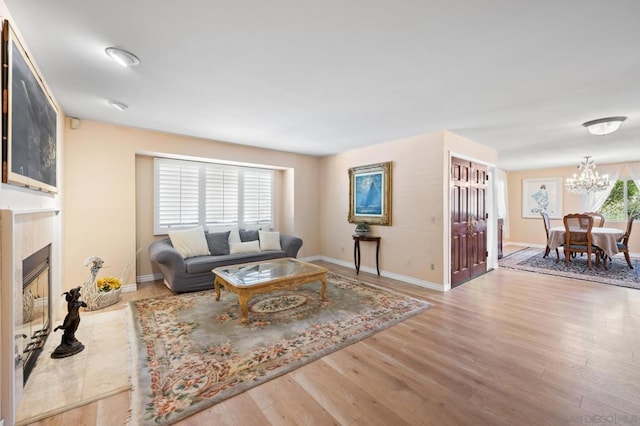 living room featuring a fireplace, an inviting chandelier, and light wood-type flooring