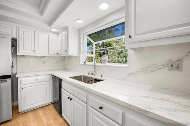 kitchen with stainless steel refrigerator, white cabinetry, sink, black dishwasher, and decorative backsplash