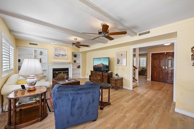 living room featuring beam ceiling, light hardwood / wood-style flooring, plenty of natural light, and ceiling fan