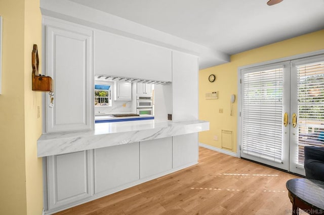 kitchen featuring white cabinets, french doors, light wood-type flooring, and white double oven