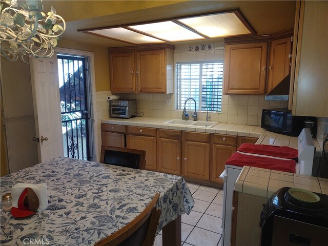 kitchen with decorative backsplash, a healthy amount of sunlight, sink, and tile counters