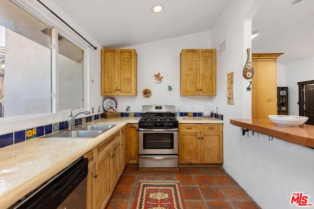 kitchen featuring appliances with stainless steel finishes, vaulted ceiling, dark tile patterned flooring, and sink