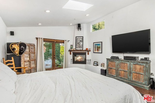 bedroom with access to outside, vaulted ceiling with skylight, wood-type flooring, and french doors