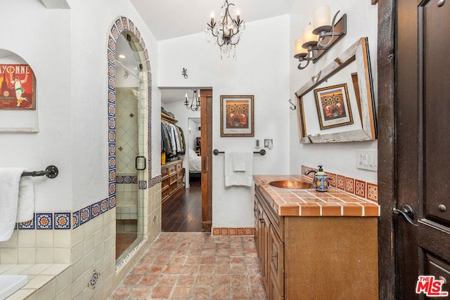 bathroom featuring an enclosed shower, vanity, vaulted ceiling, hardwood / wood-style flooring, and a notable chandelier