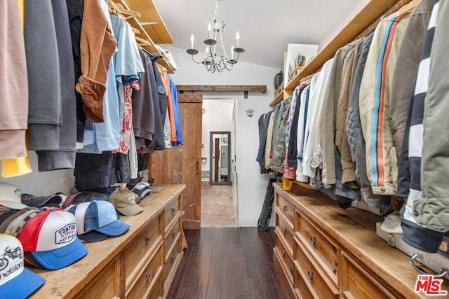 spacious closet with dark hardwood / wood-style flooring, lofted ceiling, and a notable chandelier