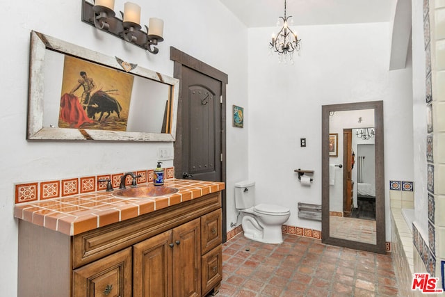 bathroom featuring a washtub, vanity, an inviting chandelier, and toilet