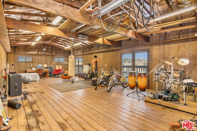 interior space featuring hardwood / wood-style flooring, vaulted ceiling, a healthy amount of sunlight, and wood walls