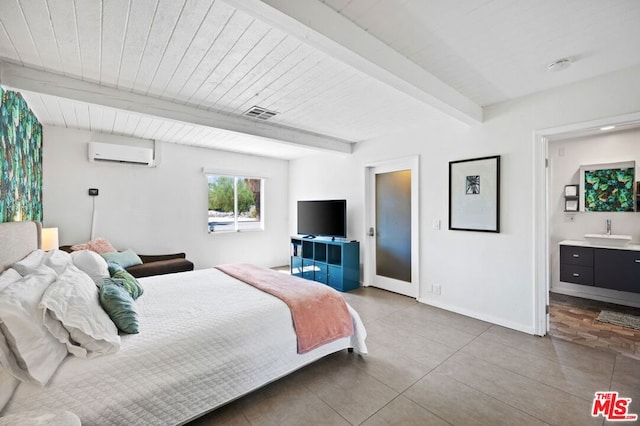 bedroom with a wall unit AC, beamed ceiling, sink, connected bathroom, and tile patterned floors