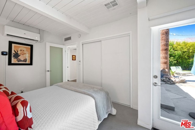 bedroom with a closet, beamed ceiling, access to exterior, a wall mounted AC, and concrete flooring