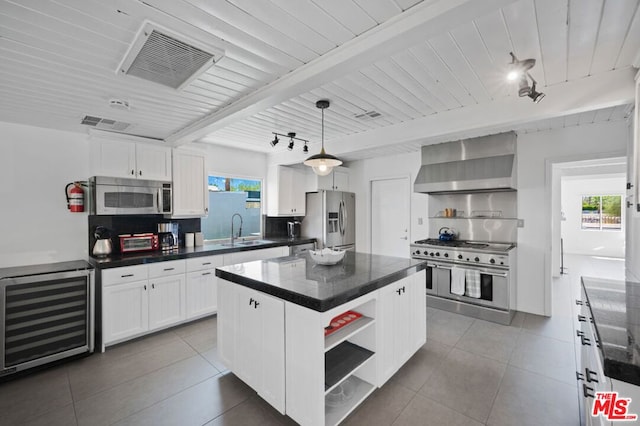 kitchen with appliances with stainless steel finishes, a healthy amount of sunlight, a kitchen island, and wall chimney range hood