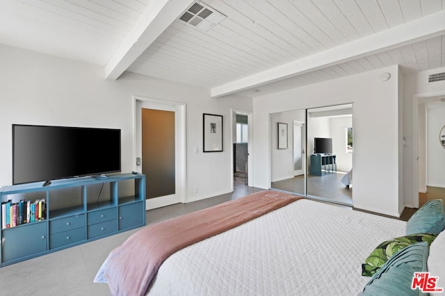 bedroom with dark tile patterned flooring, beam ceiling, and a closet