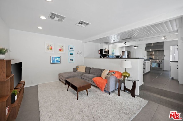 living room with beam ceiling and tile patterned floors