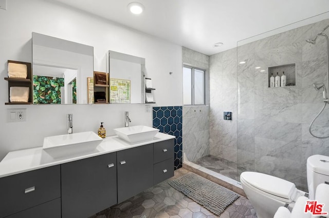 bathroom featuring a tile shower, vanity, tile walls, and toilet