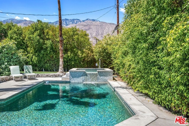 view of swimming pool with a mountain view, a patio, and an in ground hot tub