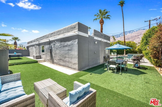 rear view of property featuring a lawn, a mountain view, and a patio area