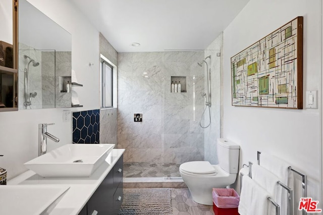 bathroom featuring a tile shower, vanity, and toilet