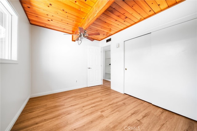 unfurnished bedroom featuring a closet, wood ceiling, light wood-type flooring, and beamed ceiling